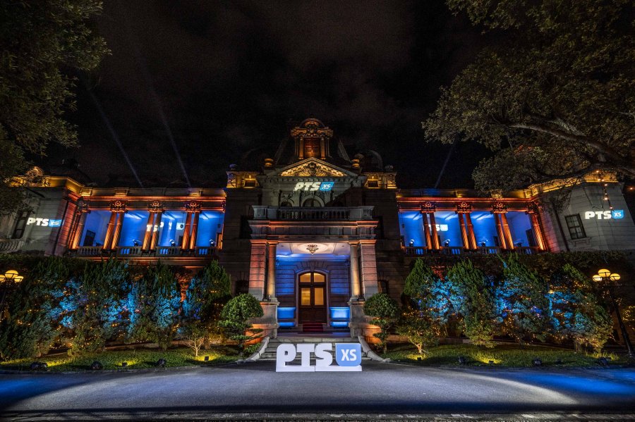 An image of a grand mansion lit up with a PTS XS sign in front.