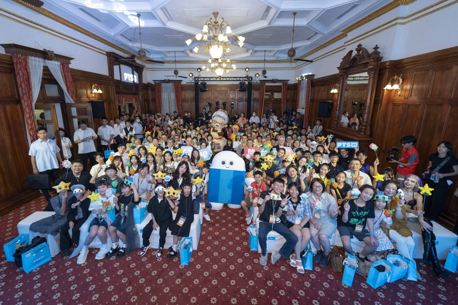 Lots of children sitting on the floor of a big grand room.