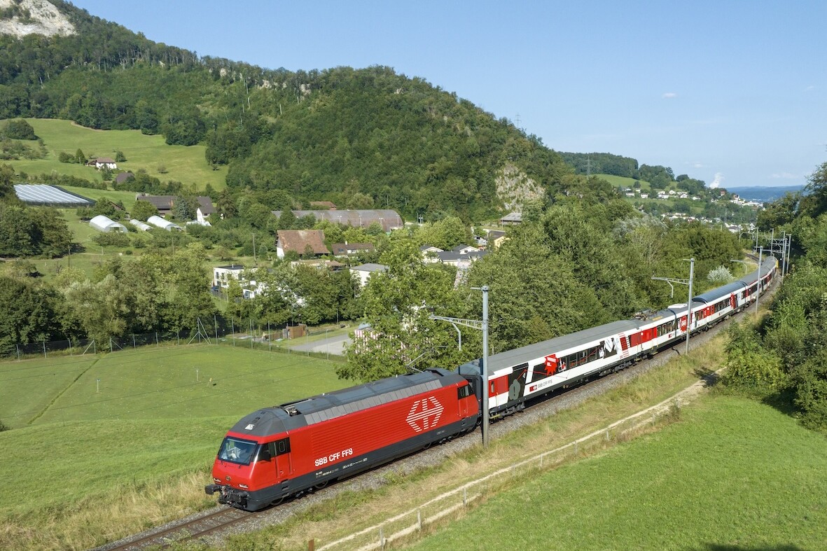 Aerial view of a train painted red and white going through the Swiss countryside