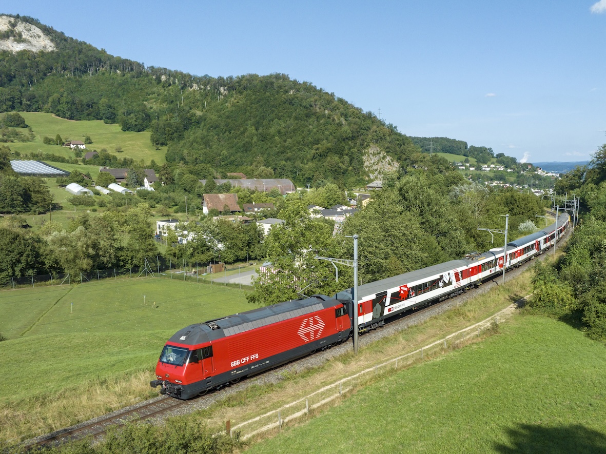 Aerial view of a train painted red and white going through the Swiss countryside